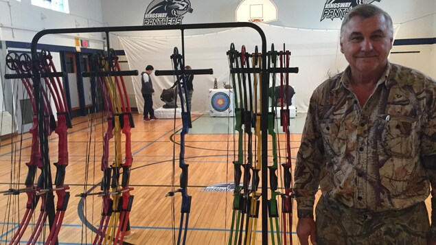 Glenn Rivard à côté d'arcs dans un gymnase. Glenn Rivard à côté d'arcs dans un gymnase.