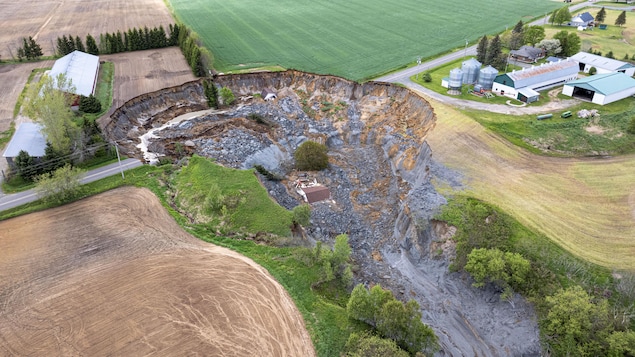 Une image aérienne d'une maison dans un cratère de boue.
