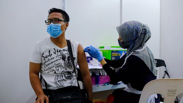Health-care worker tinurukan ang lalaki ng bakuna.