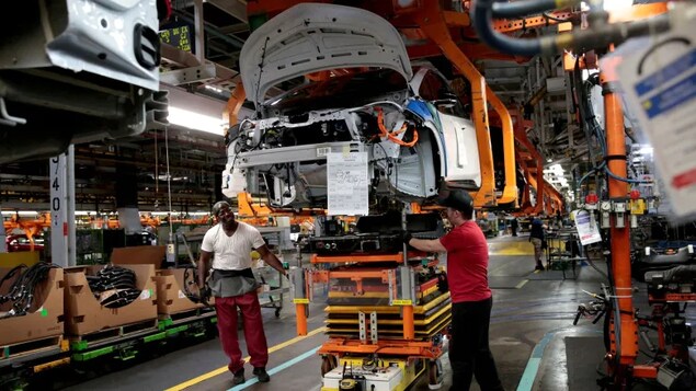 GM workers in Michigan connect a battery pack underneath a partially assembled 2018 Chevrolet Bolt EV in 2018.