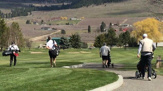 Des golfeurs sur un terrain de golf respectent 2 mètres de distance entre eux.
