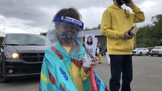 La petite Gracie, 6 ans, masquée, distribue des petits cartons à la mémoire de sa mère.