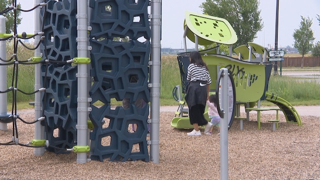 Une femme et un enfant marchent devant une structure de jeux tagguée