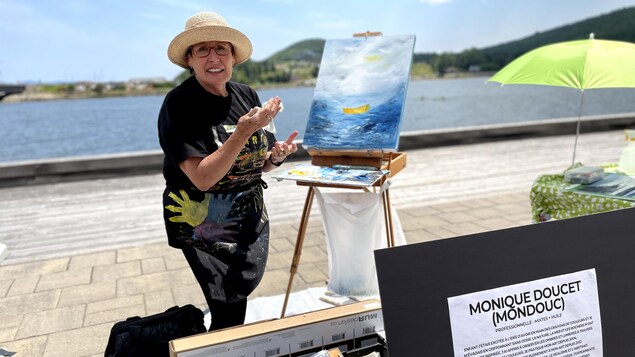 Monique Doucet peinture une toile de la mer.
