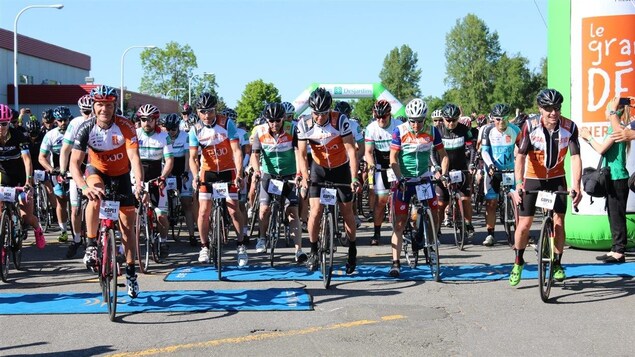 Des cyclistes sont regroupés à la ligne de départ et attendent le signal pour partir Des cyclistes sont regroupés à la ligne de départ et attendent le signal pour partir