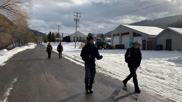 Deux jeunes hommes marchent sur une route avec deux autres marcheurs en arrière-plan.