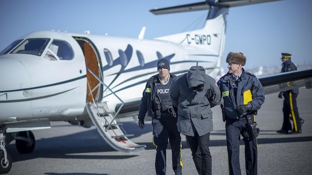 Un homme et deux agents de la GRC sont à côté d'un avion