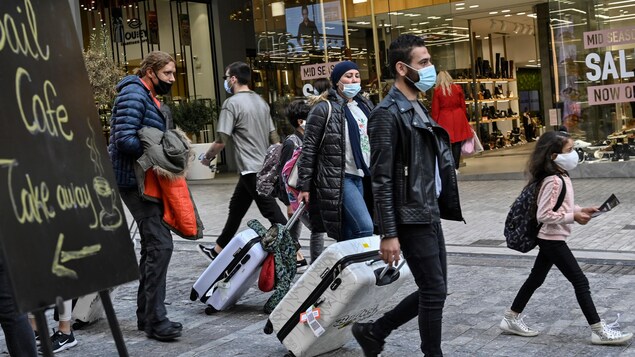 Des piétons portant des masques se promènent dans la principale rue commerciale d'Athènes.