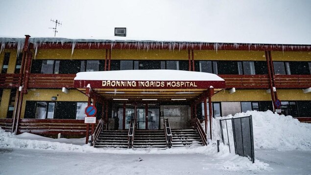 A picture of a hospital with icicles hanging off the roof. 