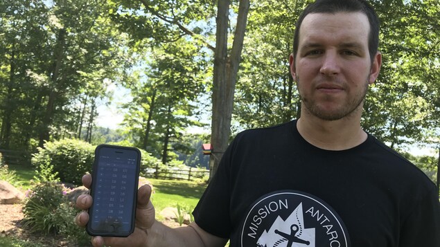 Philippe Jean tient son téléphone cellulaire dans sa main.