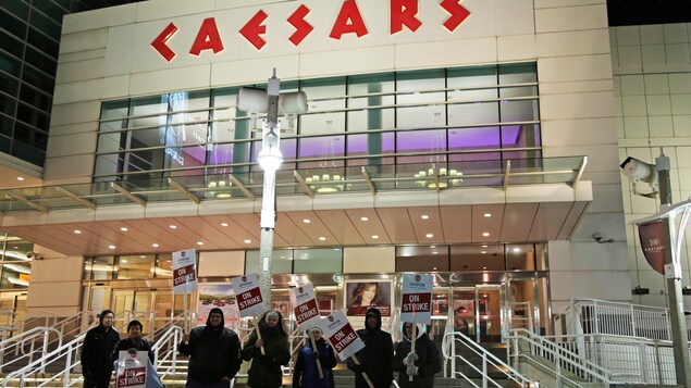 Des personnes tiennent des panneaux de grève devant l'entrée du casino