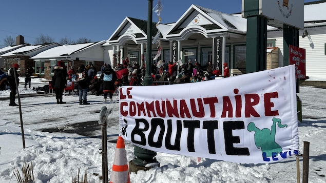 Des manifestants dans le stationnement extérieur d'une épicerie.