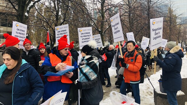 Des manifestants avec des pancartes où l'on peut lire en anglais, «en grève pour protéger une éducation de qualité et les étudiants».