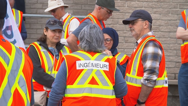 Des ingénieurs en grève avec des dossards fluo jaune et orange.