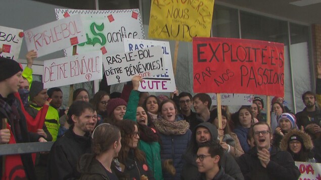 Des étudiants tiennent des pancartes.