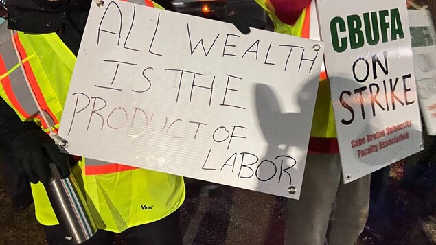 Plan rapproché de la pancarte tenue par un gréviste. Il est écrit : « Toute richesse est le produit d'un travail ».