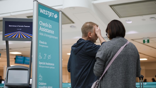 Des passagers, l'air découragé, dans la zone d'enregistrement d'un aéroport.
