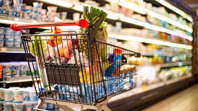 Isang grocery cart na puno ng mga gulay, prutas at mineral water.