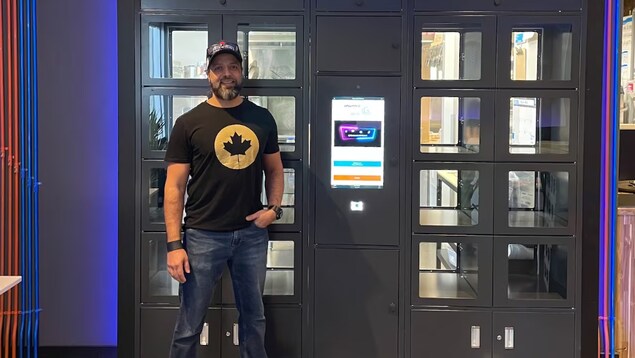 Un homme pose devant une machine de distribution de commandes de nourriture.