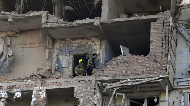 Deux secouristes circulent dans un immeuble en ruine.