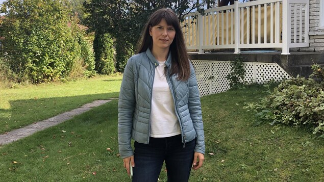 Une femme pose devant une maison.
