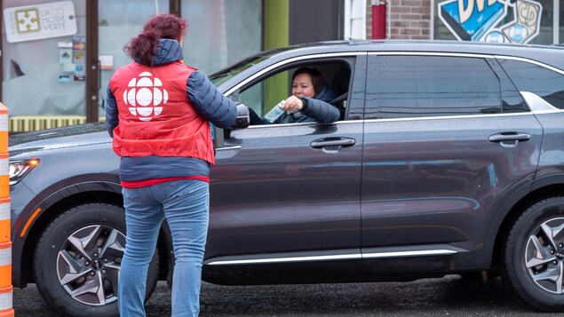 Une dame dans une voiture fait un don à une bénévole de la guignolée.