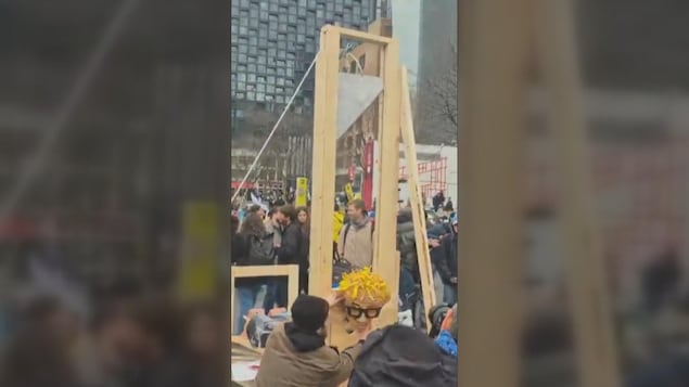 Des manifestants s'apprêtent à guillotiner une marionnette.