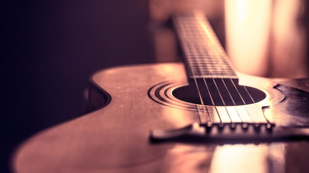 Une guitare acoustique est faiblement éclairée.