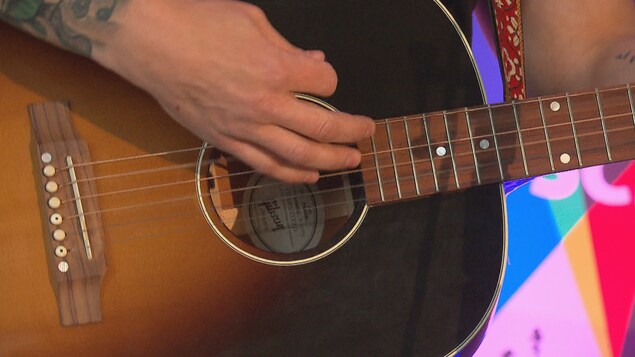 Gros plans sur un artiste qui joue de la guitare.