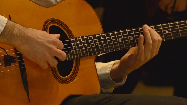 Des mains jouent de la guitare.
