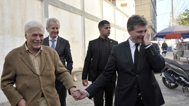 L'humoriste français Guy Bedos et l'homme politique Arnaud Montebourg se tiennent la main dans la rue lors de la campagne des primaires de la gauche en France, en décembre 2016.