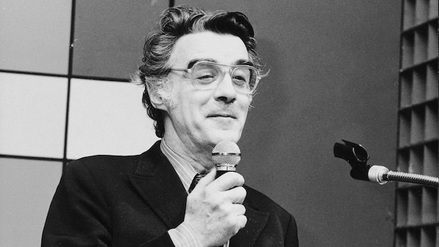Guy Mauffette tenant un micro, en studio.