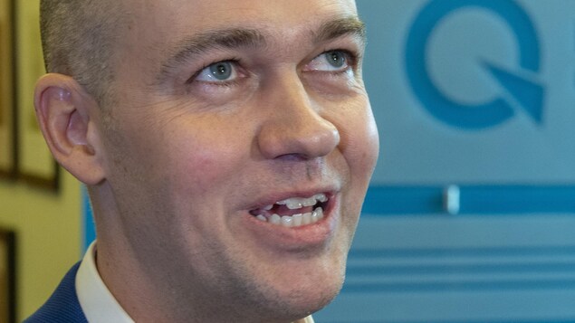 Guy Nantel devant le logo du Parti québécois.