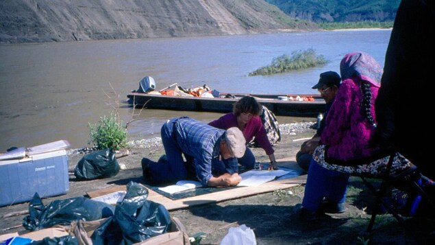 Un groupe de personnes est penché sur une carte près d'un lac.