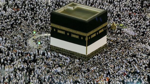 Des musulmans s'agenouillent au pied de la Kaaba, monument cubique noir et blanc de près de 13 mètres de hauteur. Des musulmans s'agenouillent au pied de la Kaaba, monument cubique noir et blanc de près de 13 mètres de hauteur.