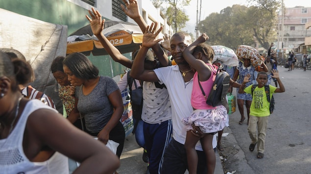 Haitianos huyen con las manos en alto.