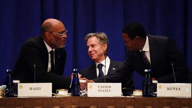 MM. Henry et Mutua se serrent la main devant M. Blinken.