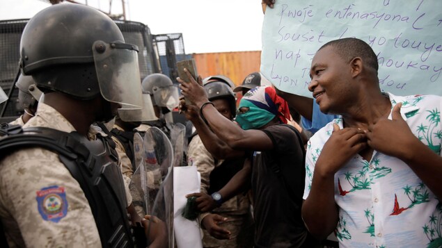 Un manifestant réclamant la démission du président haïtien devant les forces de la police nationale dans les rues de Port-au-Prince.