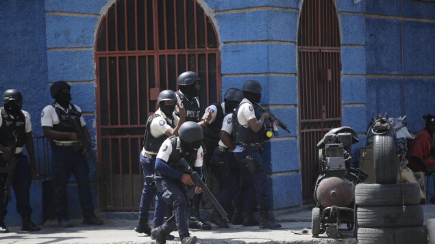 Police officers take cover during an anti-gang operation in the Lalue neighborhood of Port-au-Prince, Haiti, on March 3, 2023. (Odelyn Joseph/The Associated Press)

