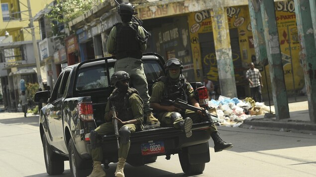Des hommes armés en uniforme à bord d'un véhicule.