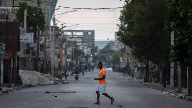 A man is crossing an empty street in Port-au-Prince.