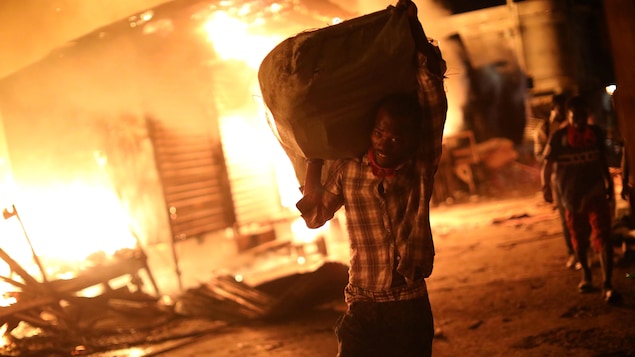 Un homme transporte un sac sur son épaule avec le feu derrière lui. Un homme transporte un sac sur son épaule avec le feu derrière lui.