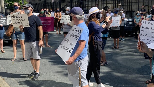 Des gens manifestent devant l'édifice de l'Assemblée législative.