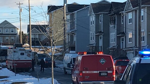 Des véhicules de police et de pompiers devant la maison ravagée par l'incendie