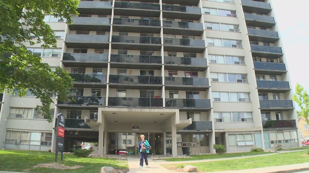 Photo d'une femme devant un édifice d'appartements de plusieurs étages Photo d'une femme devant un édifice d'appartements de plusieurs étages
