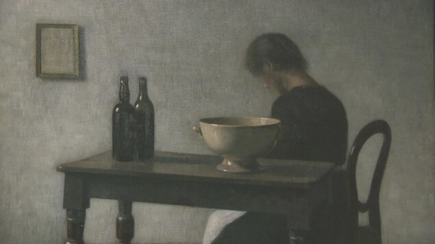 Une femme à la tête penchée est assise près d'une table sur laquelle sont posées deux bouteilles de vin et un bol sur pied. Une femme à la tête penchée est assise près d'une table sur laquelle sont posées deux bouteilles de vin et un bol sur pied.