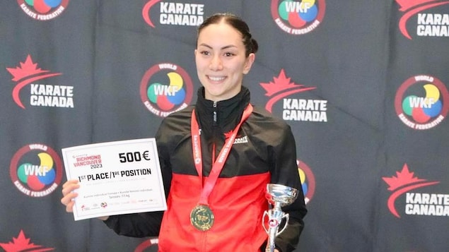 Hana Furumoto-Deshaies pose pour la caméra avec sa médaille d'or et son trophée.
