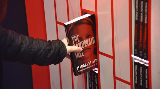 Una mano toma la novela "El cuento de la criada".