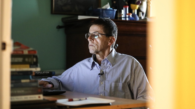 Hassan Diab est assis devant un ordinateur, à côté d'une pile de livre, dans son bureau à domicile. Hassan Diab est assis devant un ordinateur, à côté d'une pile de livre, dans son bureau à domicile.
