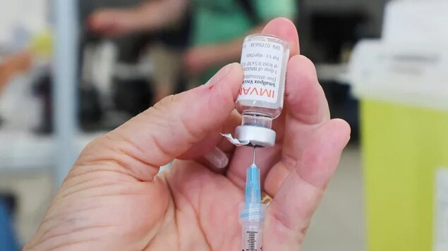 Kamay may hawak na syringe at vial ng Imvamune vaccine.